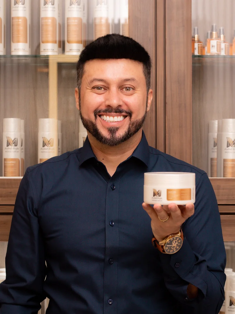 Michaell Douglas sorrindo no atelier segurando o pote da Máscara Premium da linha profissional